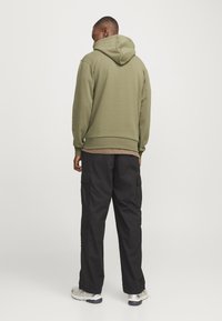 Olive green hoodie with a drawstring hood, ribbed cuffs, and hem, paired with loose black cargo pants featuring side pockets.