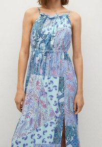 Maxikleid in Blau mit gemustertem Design, das eine Mischung aus Paisleymustern zeigt, verstellbaren Spaghettiträgern und einem Taillengürtel. Mit einem hohen Schlitz bis zum Oberschenkel.