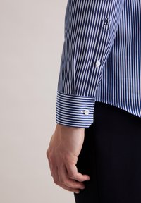 Blauw-wit gestreepte blouse met knoopmanchetten, getailleerde pasvorm en gladde katoenstof. Accentuert met duidelijke horizontale en verticale strepen.