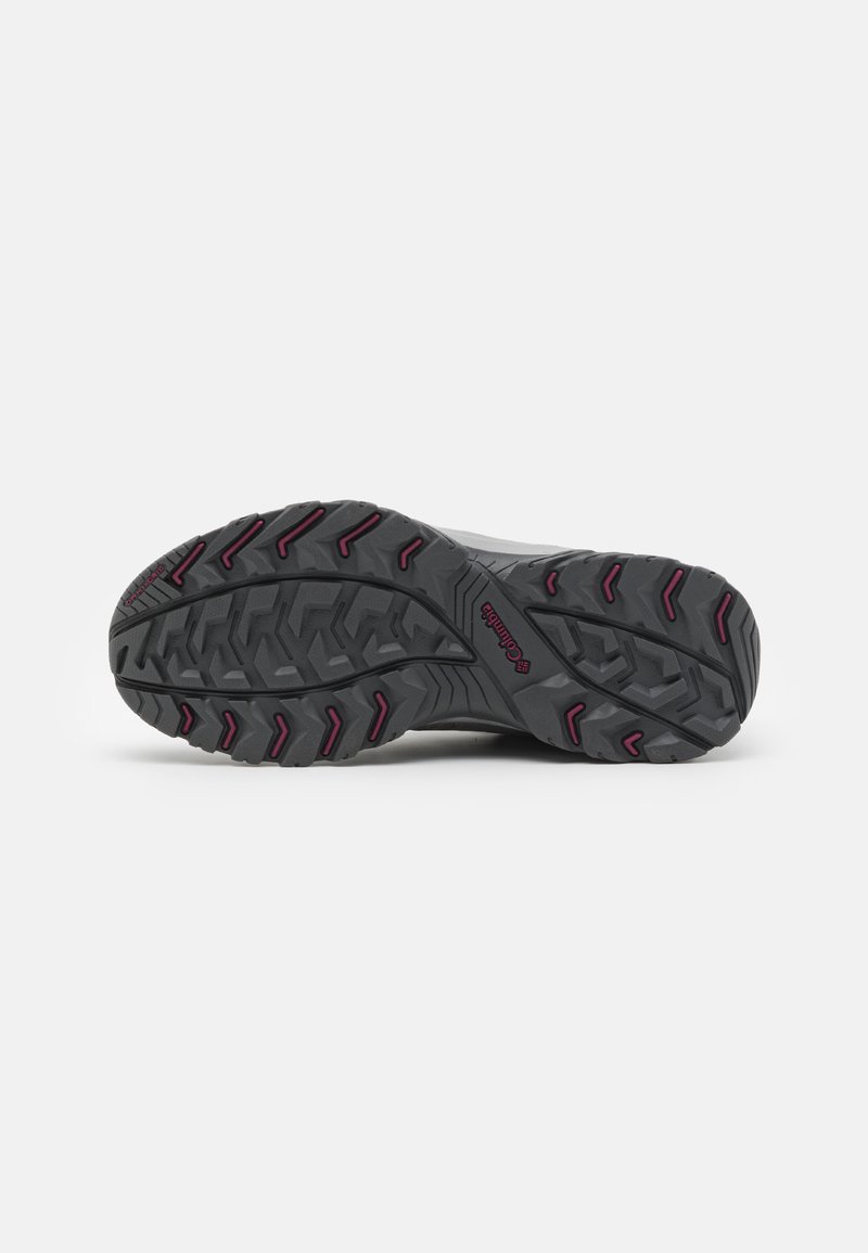 Semelle d'une chaussure de randonnée grise avec des profondeurs de crans et des accents rouges, comportant un logo "Columbia" au centre.