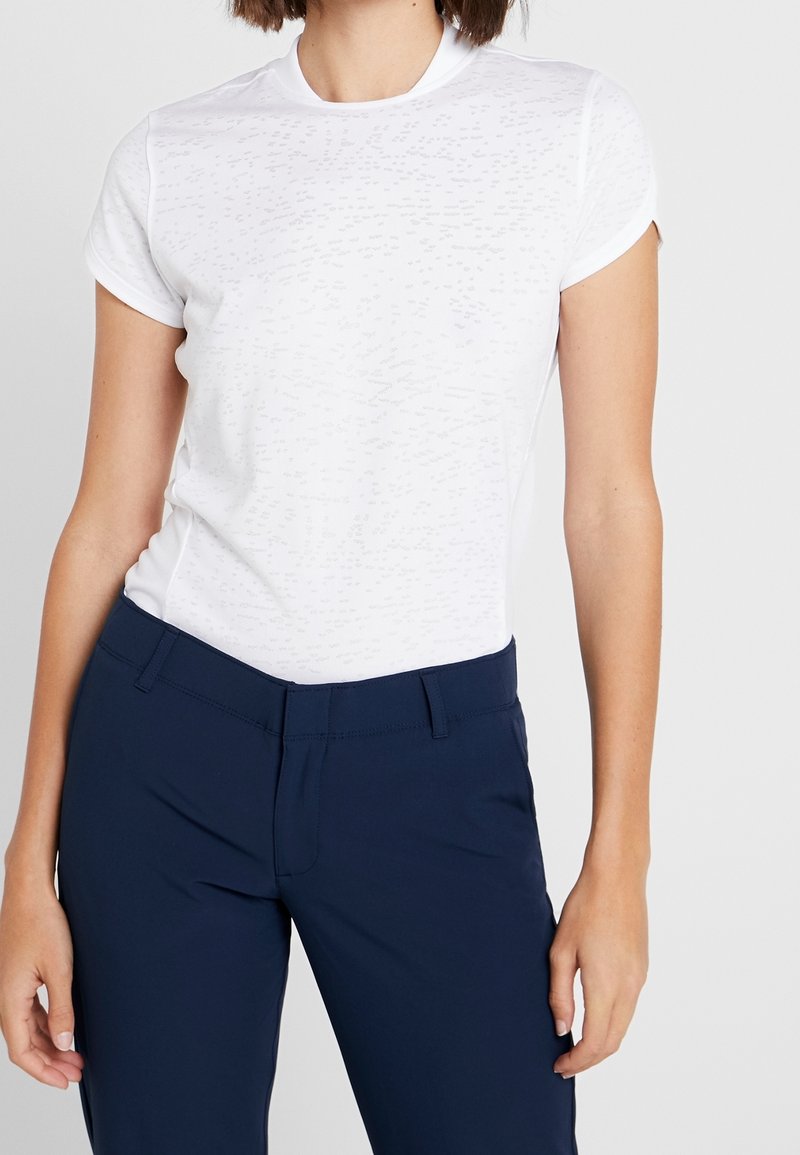 Vit t-shirt med kort ärm och en subtil texturerad mönster, ihopparad med skräddarsydda marinblå byxor med platt front och fickor.