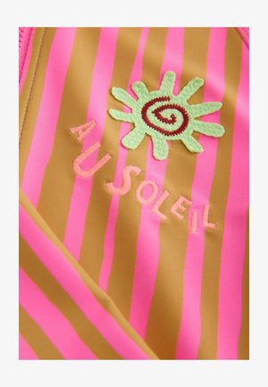 Uimapuku, jossa on rohkeat vaaleanpunaiset ja ruskeat raidat, kirjailtu vihreällä auringon kuviolla ja teksti "AU SOLEIL" vaaleanpunaisella langalla. Pehmeä rakenne.