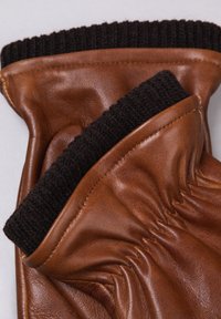 Brown leather glove featuring a textured black knit cuff. The glove exhibits soft leather with visible stitching and a gathered design.
