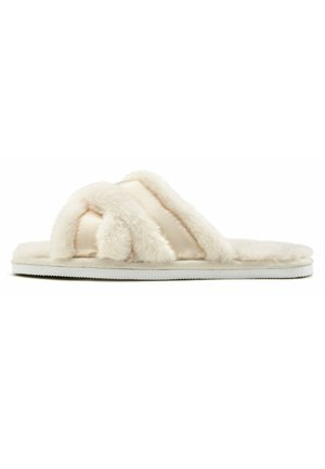 Des chaussons flous de couleur crème avec un design entrecroisé, une texture douce et une semelle en caoutchouc blanc. Convient pour une utilisation en intérieur.