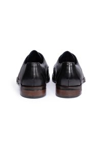 Zwarte leren schoenen met een gladde textuur, met een lage hak en houten accenten. Vormgegeven met een ronde neus en minimale stiksels.
