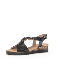 Sandale en cuir noir avec un bout ouvert, design à brides croisées et sangle arrière adjustable. Elle présente un talon en coins texturé avec motif animal.