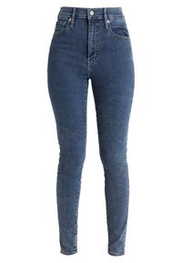 Vysoké modré džíny s úzkým střihem, vyrobené z denimu. Mají klasický design s pěti kapsami a mírně vybledlou texturu.