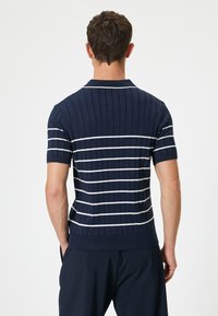 Polo de rayas marinas con diseño de textura acanalada, featuring rayas horizontales blancas y mangas cortas. Ajuste entallado con cuello.
