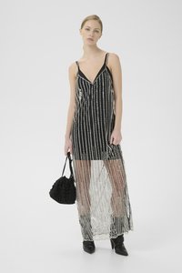 Rochie lungă alb-negru cu embellishments de mărgele verticale, bretele subțiri, decolteu adânc în formă de V și un overlay transparent. Asortată cu o geantă texturată neagră.