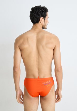 Orange Schwimmbrief mit enganliegendem Schnitt, elastischem Bund und gesticktem Logo-Detail auf der Rückseite. Glatter Stoff. 
