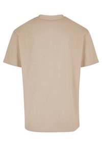 Camiseta beige de manga corta hecha de tela suave, con un cuello redondo clásico y un dobladillo recto. Sin patrones ni acentos visibles.