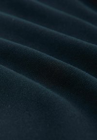 Dunkles Gewebe mit weicher Textur, das subtile Rillen und ein leicht dehnbares Aussehen aufweist. Die Farbe ist ein tiefes, reichhaltiges Marineblau.