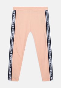 Barack színű leggings, amelynek oldalán tengerészkék csík található, rajta a "GUESS LOVE" felirattal ismétlődve. Puha, rugalmas anyagból készült, testhezálló fazonban.