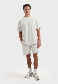 Lichtgrijze katoenen t-shirt en bijpassende shorts. Het t-shirt heeft een ronde hals en korte mouwen, met een klein bedrukt logo op de borst.