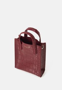 Burgundy fejk krokodilläderhandväska med dubbla handtag, rektangulär form och präglingstextur. Har en guldlogotyp som accent.