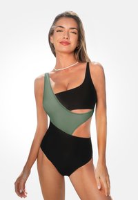 Eén stuk badpak met een groene en zwarte kleurblokontwerp, asymmetrische uitsparingen en een hoog uitgesneden been. Glad, rekbaar stof.