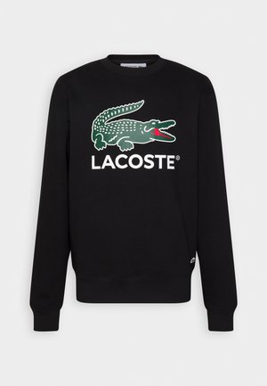 Černá mikina s dlouhým rukávem a kulatým výstřihem s velkým zeleným logem krokodýla a nápisem "LACOSTE" na hrudi.