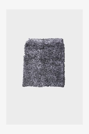 Tappeto grigio shaggy con superficie testurizzata, caratterizzato da un design soffice. I bordi sono irregolari, migliorando l'aspetto morbido e accogliente.