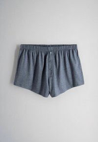 Boxeri gri pentru bărbați, din bumbac, cu talie elastică și capse cu trei nasturi, pe fundal simplu deschis.