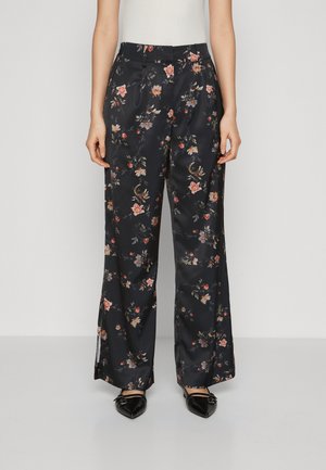 Pantaloni ampi in satin floreale di colore blu navy con fiori multicolori. Caratterizzati da una vita alta e dettagli plissettati, abbinati a scarpe basse nere a punta.