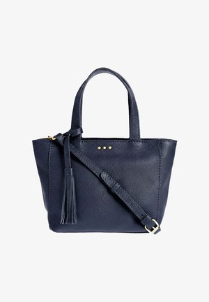 Sac fourre-tout en cuir bleu marine avec double poignées, bandoulière ajustable, détail pompon et trois petits clous dorés sur le devant.