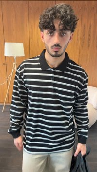 Black and white striped long-sleeve polo shirt with a collar. Displaying a relaxed fit; no patterns, made of a soft fabric. Light-colored pants.