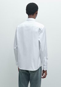 Witte lange mouwen overhemd met een klassieke kraag, rug yoke-ontwerp en manchet, gecombineerd met lichtblauwe denim jeans.