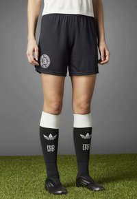 Black soccer shorts with a ribbed texture and white logo at the hem, paired with black knee-length socks featuring white accents and logo.