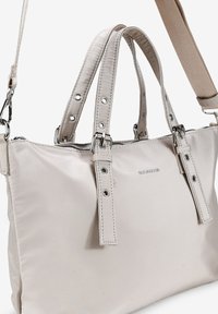 Bolso sintético de color claro con dos asas cortas y una correa para el hombro desmontable. Presenta herrajes plateados y detalles de costura visibles.