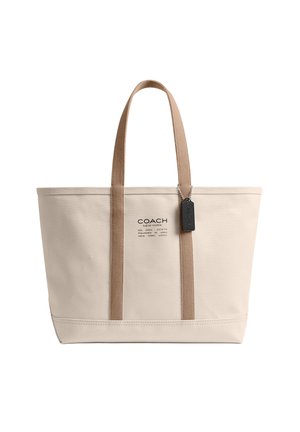 Bolso tote de lona beige con asas color cuero, etiqueta negra de Coach y logo de Coach New York en el centro delantero.