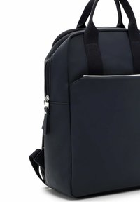 Zwarte rugzak met een gladde, matte textuur. Voorzien van dubbele handvatten, verstelbare banden en een voorvak met een subtiele witte accent.