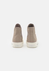 Sneaker alte in pelle beige con una superficie liscia, dotate di suole in gomma bianche e un logo a stella sul tallone.