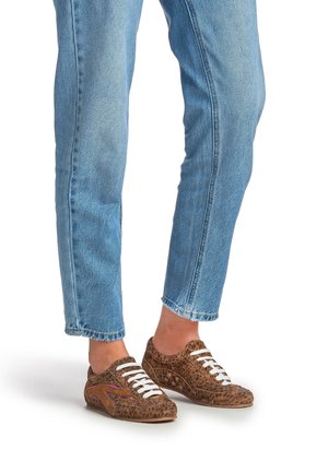 Baskets à imprimé animalier marron avec lacets blancs, bout arrondi et dessus texturé. Portées avec un jean bleu clair légèrement fuselé.
