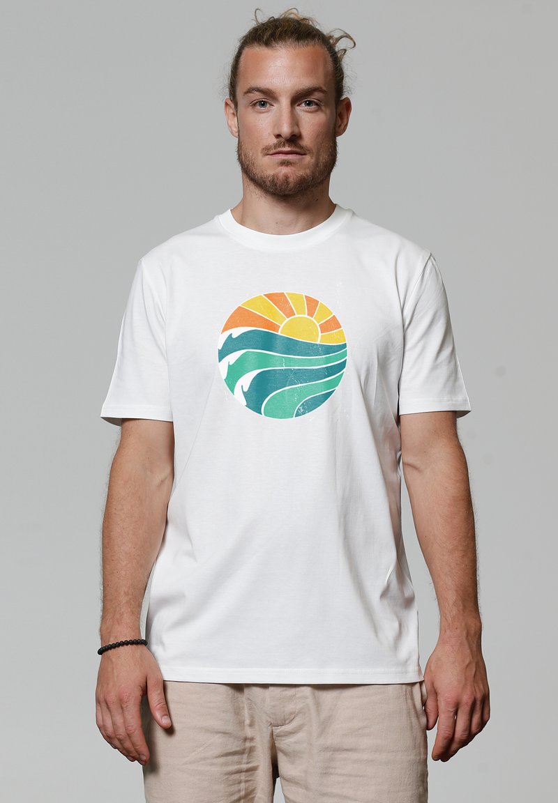 Witte katoenen t-shirt met een ronde afbeelding van een oranje zon en blauw-groene golven, wat een strandthema ontwerp creëert.