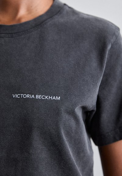 Temno siva bomba T-shirt iz bombaža z okroglim ovratnikom in kratkimi rokavi. Na levi strani prsnega dela prikazuje besedilo "VICTORIA BECKHAM" v beli barvi.