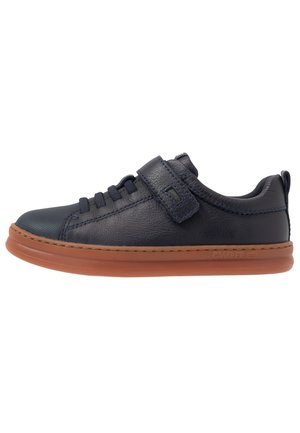 Marinblå lädersneakers med rund tå, texturerad yta, snörning och kardborreband, samt en tan gummisula.