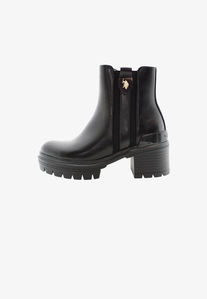 Botas de cuero negras hasta el tobillo con un tacón grueso, paneles elásticos laterales y un acento de logo en la asa. Suela de goma texturizada.