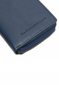 Portafoglio in pelle blu con superficie testurizzata, dotato di zip e marchio in rilievo all'esterno. Bordo liscio e dettagli di cucitura.