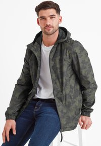 Dark green camo jacket with a hood, lightweight material, zippered front, elastic cuffs, and contrasting pattern detail. Worn over a white shirt.