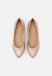 Ballerines couleur nude avec une finition lisse et brillante, un design à bout pointu et une silhouette minimaliste. L'intérieur est beige.