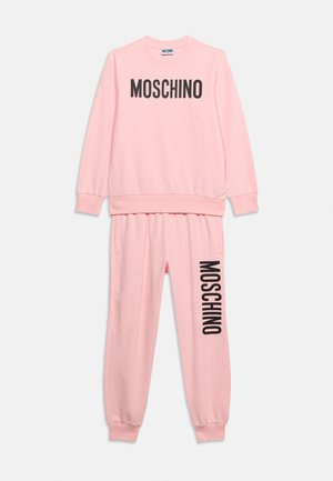 Conjunto de sudadera y pantalones deportivos en rosa claro con texto negro "MOSCHINO" en el pecho y la pierna izquierda, puños y cintura elásticos.