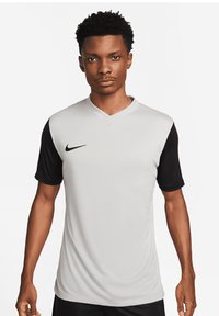 Maglietta sportiva Nike con un corpo grigio chiaro, maniche corte nere, design a scollo a V e un piccolo logo nero sul petto.