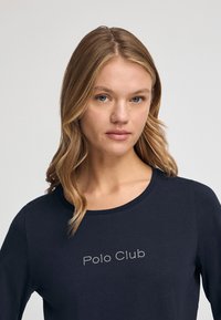 Navyblaues Langarmshirt aus Baumwolle mit rundem Halsausschnitt. Mit "Polo Club" in Kristallakzenten über der Brust. Glatte Textur.