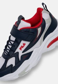 Sneaker in pelle blu navy e mesh bianco con accenti rossi. Presenta una strap in Velcro, punta tonda, colletto imbottito e una suola bianca spessa con dettagli rossi.