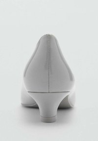 Scarpa con tacco alto grigia e lucida, con punta affusolata e design del tacco curvo. I dettagli delle cuciture aggiungono texture alla silhouette elegante.