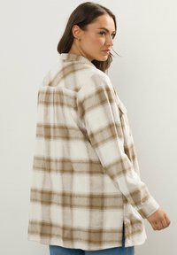 Keve könnyű kockás ing krém és barna színekben. Jellemzője a gombos elülső rész, hosszú ujjú, és oldalt rés van. Puha anyagból készült, laza szabású.