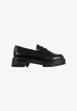 Mocassin en cuir noir à semelle épaisse, talon relevé et semelle extérieure rainurée, style slip-on avec détail de bride sur le dessus.