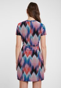 Abito a maniche corte con vita aderente, caratterizzato da un motivo zigzag multicolore in sfumature di rosa, blu e nero. Tessuto dalla texture liscia.
