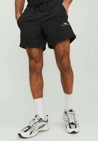Schwarze Sportshorts aus leichtem Material, mit einem elastischen Bund und seitlichen Taschen. Akzentuiert mit weißem Logo-Text.