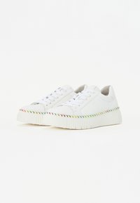 White sneakers with a textured sole, featuring a multicolored braided accent along the platform and classic lace-up design.